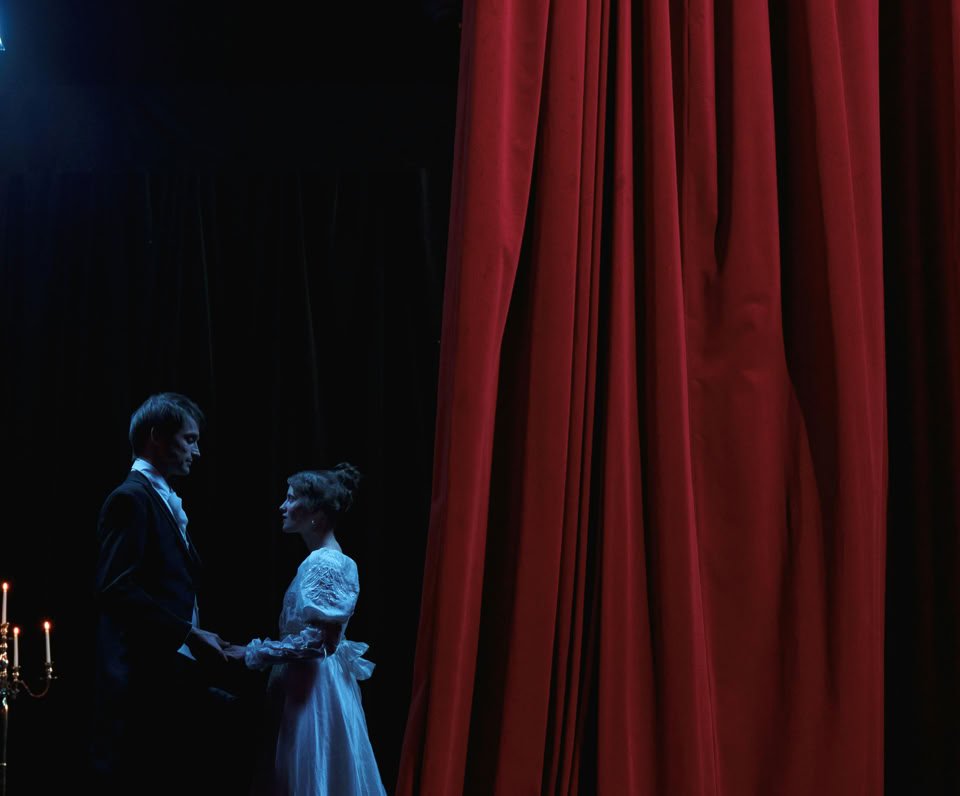 A captivating stage scene featuring a man and woman in romantic attire, lit by dramatic stage lights.