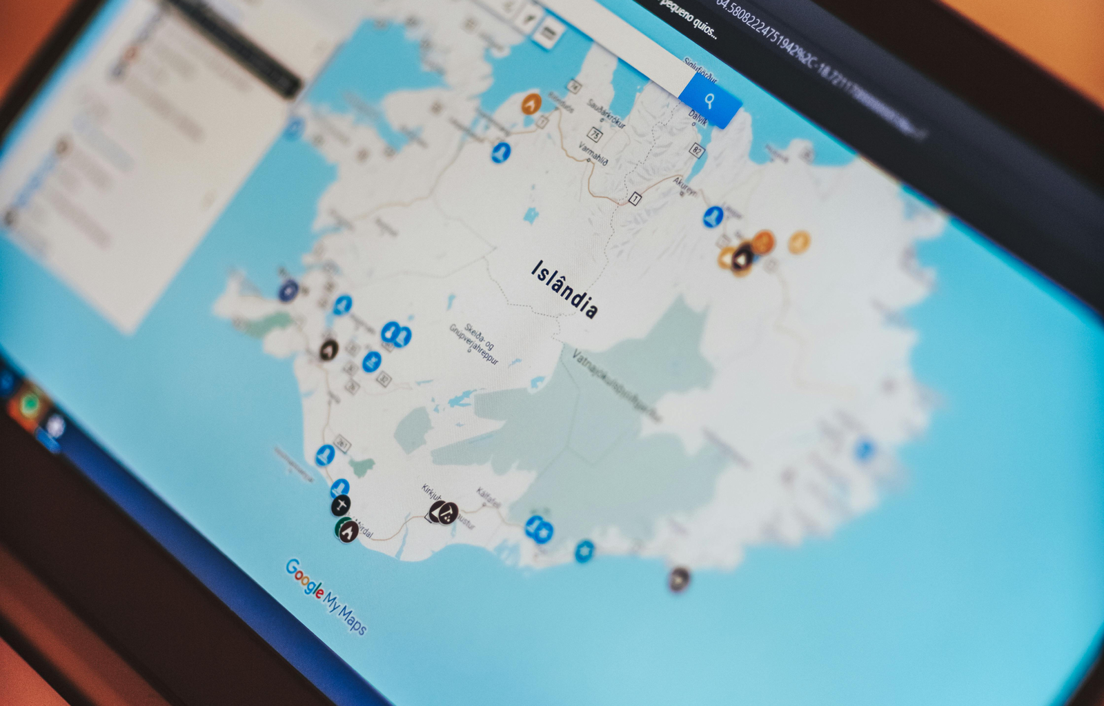 From above of open netbook with geographic map and bright symbols on web page